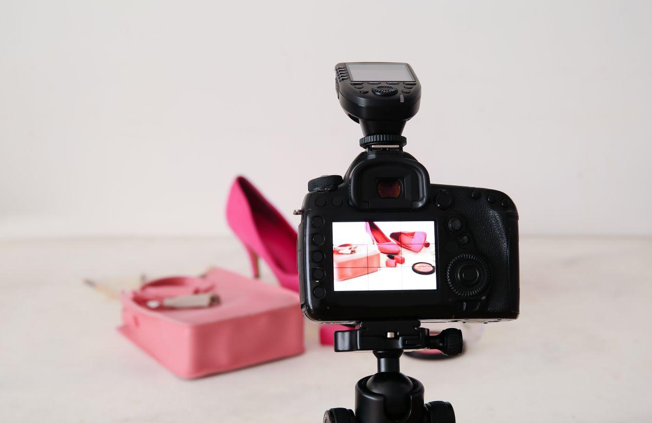 Eine DSLR-Kamera fotografiert pinke High Heels und Accessoires vor einem weißen Hintergrund – ein Beispiel für professionelle Amazon Produktfotos mit optimaler Beleuchtung.